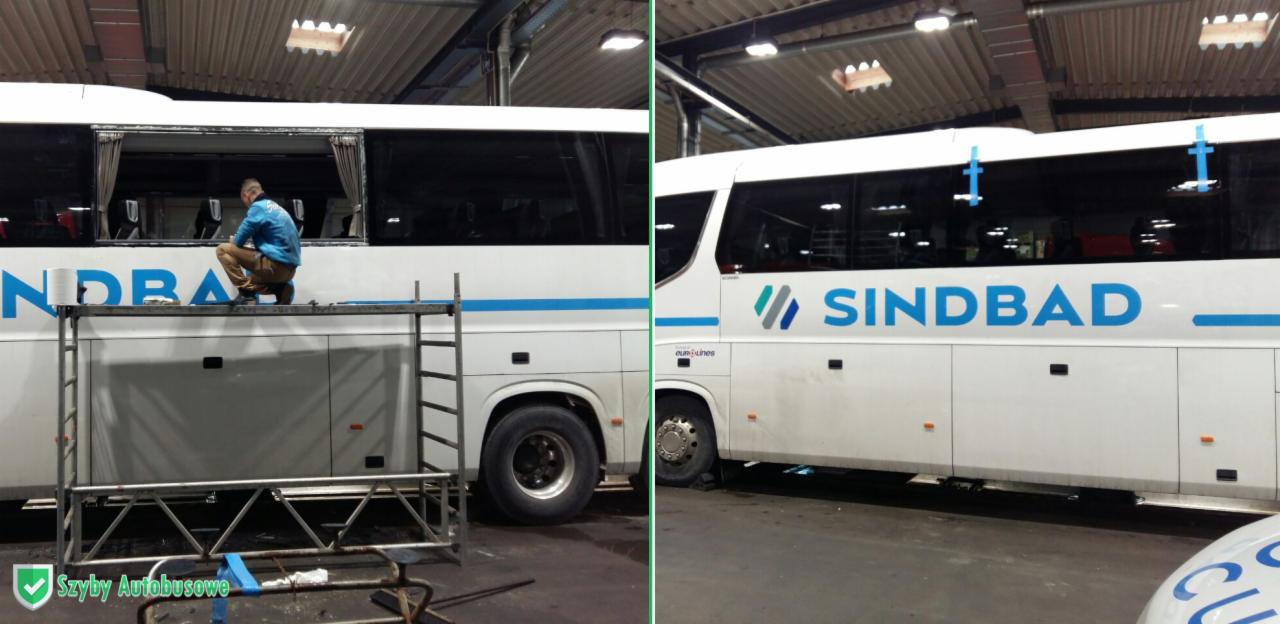 Pracownik na rusztowaniu montuje szybę w autokarze Sindbad, zabezpieczonym taśmą, widok z boku na warsztat.