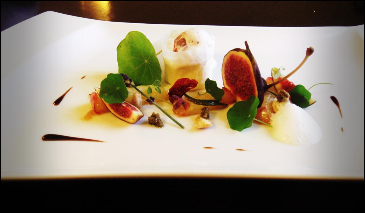 Elegancko podane danie z figami, pianką, ziołami i sosem balsamicznym na białym, prostokątnym talerzu.