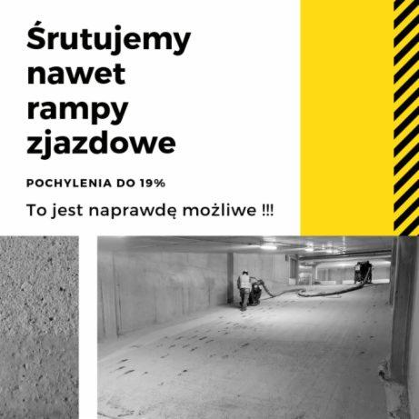 Pracownicy w kombinezonach czyszczą maszynowo rampę zjazdową w pochylonym tunelu, widoczne ślady czyszczenia na betonowej powierzchni. Na górze grafika reklamowa z hasłem 'Śrutujemy nawet rampy...