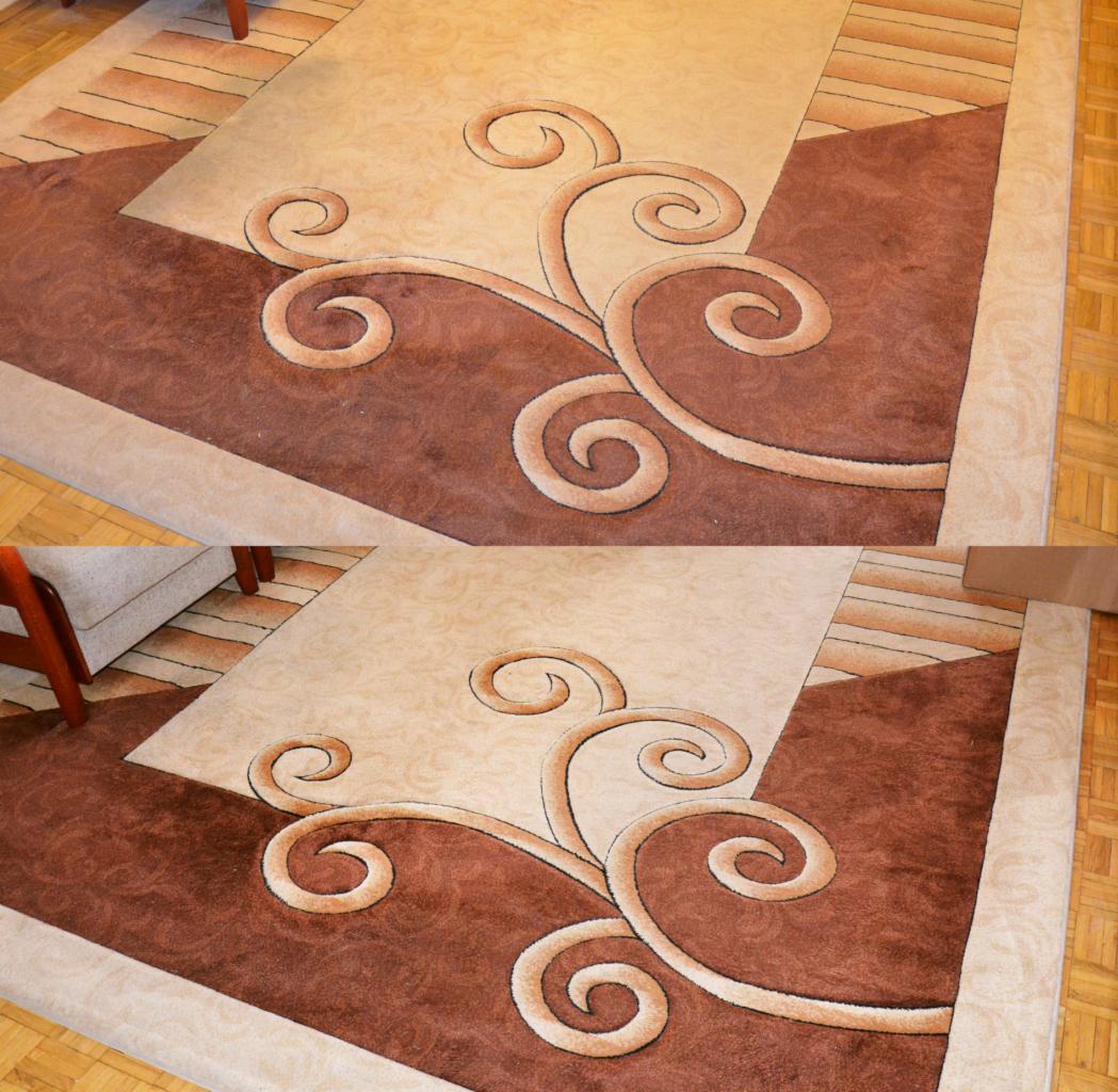 Beżowo-brązowy dywan z abstrakcyjnym wzorem spiralnym na drewnianej podłodze, widoczny fragment krzesła.