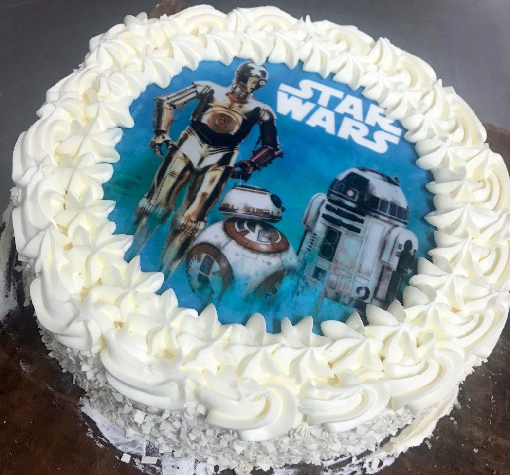 Okrągły tort z białym kremem i jadalnym nadrukiem Star Wars przedstawiającym C-3PO, BB-8 i R2-D2.