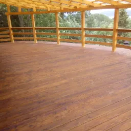 Zadaszony taras drewniany z balustradą, widok na zieleń z perspektywy podłogi, drewno w odcieniach brązu.