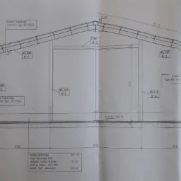 Rzut przekroju A-A budynku gospodarczego z wymiarami, detalami konstrukcyjnymi i specyfikacją materiałową, wykonany w skali 1:50.