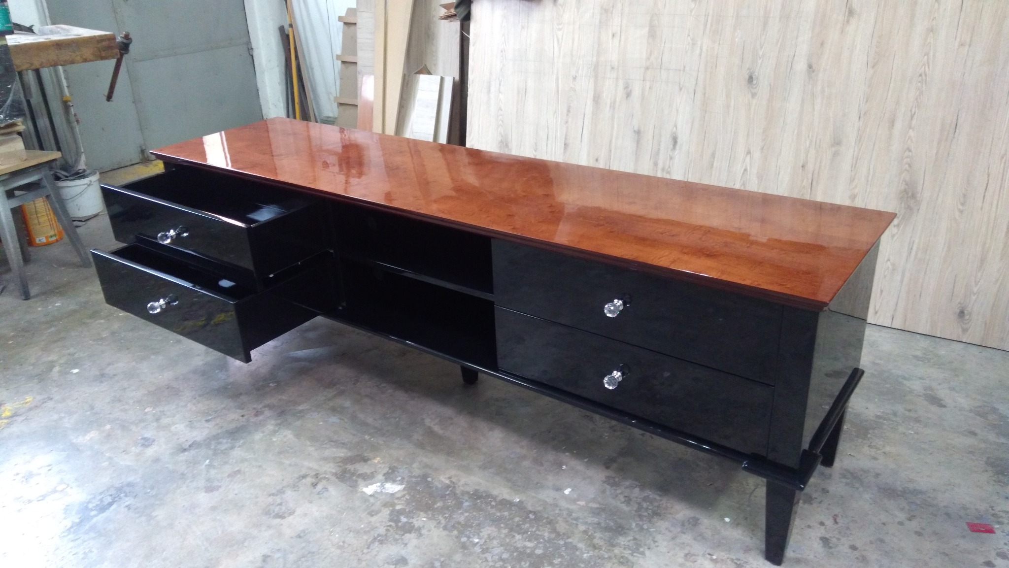 Lakierowana komoda RTV w stylu retro, z otwartymi szufladami i drewnianym blatem w odcieniach brązu, na tle warsztatu.