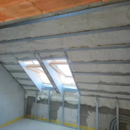 Poddasze w Gryfinie w trakcie ocieplania pianą poliuretanową, widoczne metalowe profile konstrukcyjne i okna dachowe