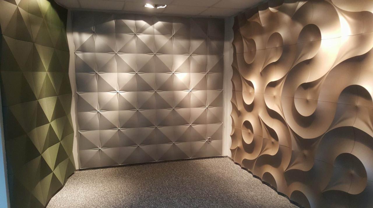 Pokój z trójwymiarowymi panelami ściennymi o różnych wzorach i kolorach: zielonym, srebrnym i beżowym, oświetlonymi punktowo od góry.