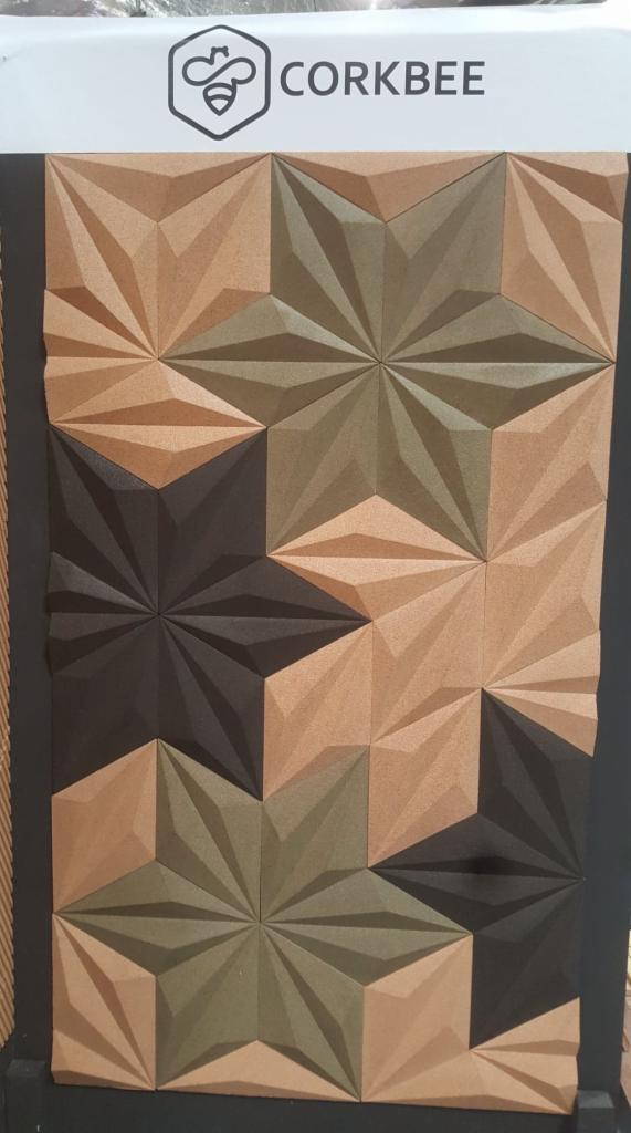 Dekoracyjne panele korkowe 3D w odcieniach brązu, zieleni i czerni, tworzące geometryczny wzór gwiazdy, prezentowane w Warszawie, z widocznym logo producenta 'CORKBEE' u góry.