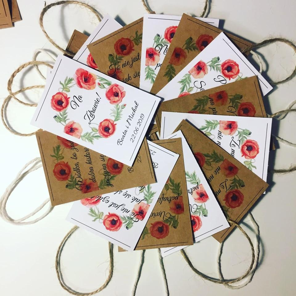 Stos kart okolicznościowych z motywem maków i personalizowanymi napisami, ułożonych na sznurku jutowym, wykonanych dla klientów z Wejherowa.