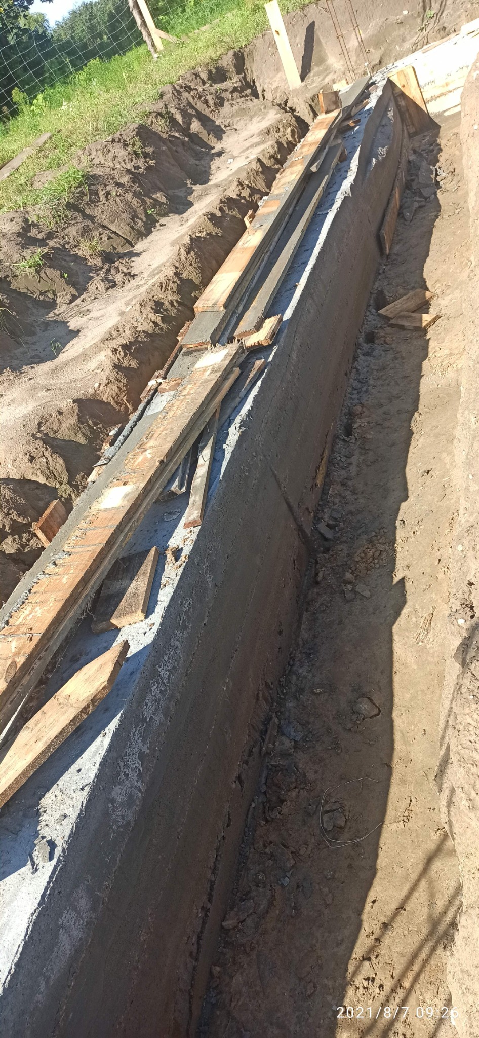 Wykop z wylanym fundamentem w Gdyni, z widocznymi deskami szalunkowymi i ziemią po bokach.