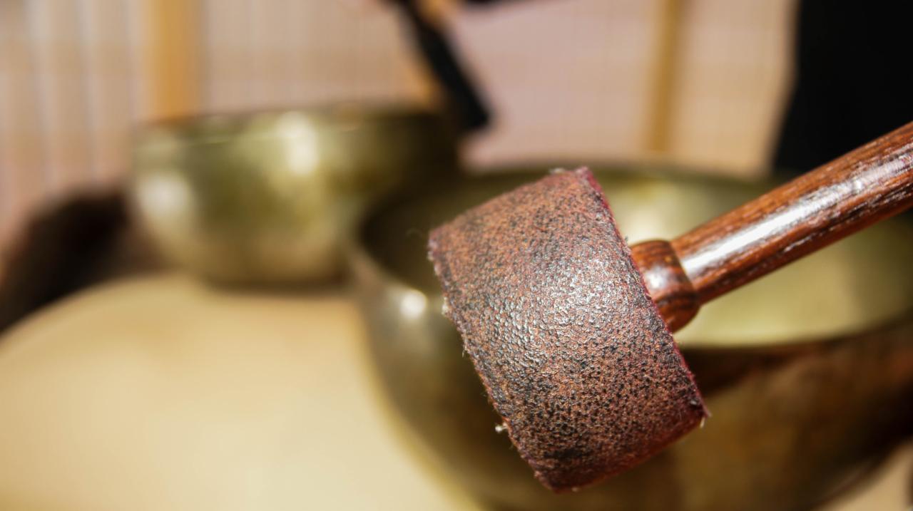 Bliski plan pałeczki z brązową końcówką do misy tybetańskiej, obok widoczna druga misa w tle.