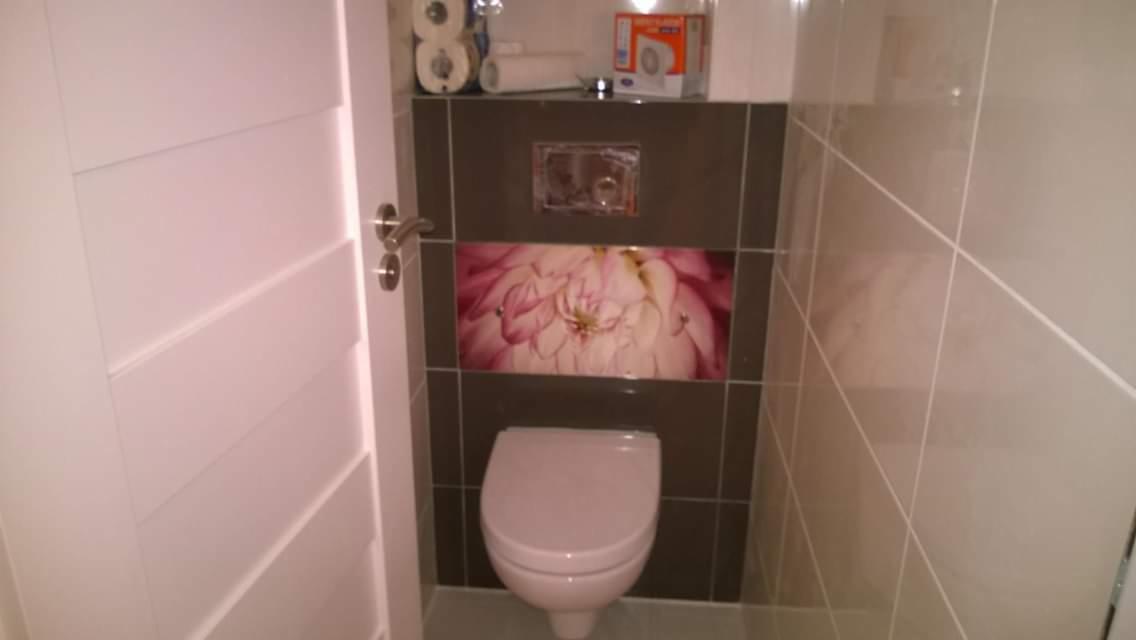 Nowoczesna łazienka z podwieszaną toaletą, ozdobiona płytkami z motywem kwiatowym i białymi płytkami na ścianach, widoczna biała, designerska drzwi do łazienki.