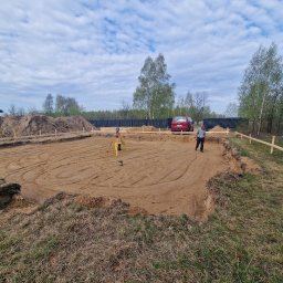 FINISZ USŁUGI REMONTOWO BUDOWLANE SPÓŁKA Z OGRANICZONĄ ODPOWIEDZIALNOŚCIĄ SPÓŁKA Z OGRANICZONĄ ODPOWIEDZIALNOŚCIĄ - Wytyczony teren pod budowę domu jednorodzinnego z widocznym niwelatorem i drewnianymi stemplami szalunkowymi.