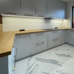 Szara kuchnia z drewnianym blatem i złotymi uchwytami, oświetlenie LED pod szafkami, marmurowe płytki podłogowe. Nowoczesny design, widok ukośny.