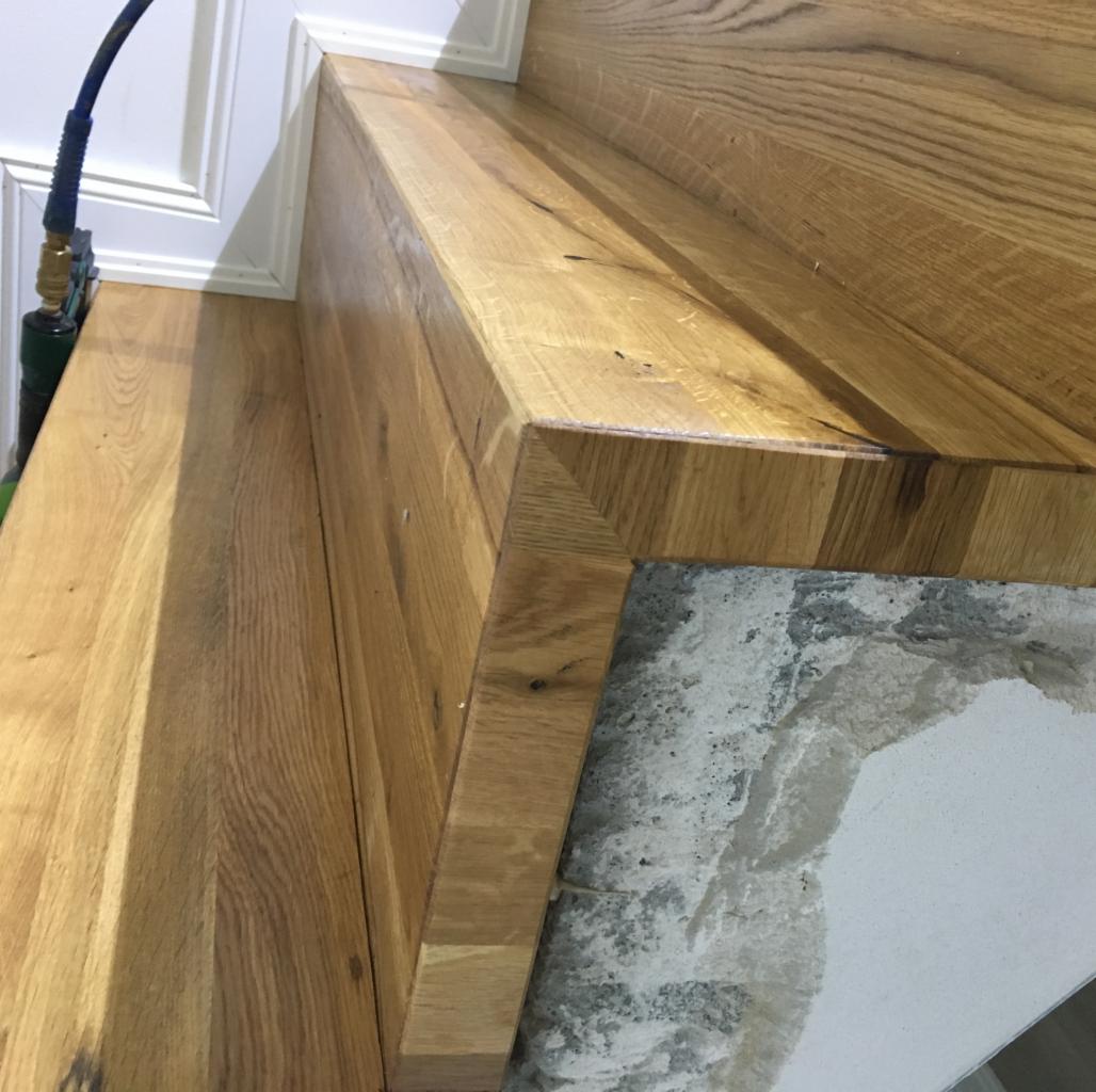 Drewniane schody z widocznym fragmentem ściany z surowego betonu i narzędziem pneumatycznym w rogu