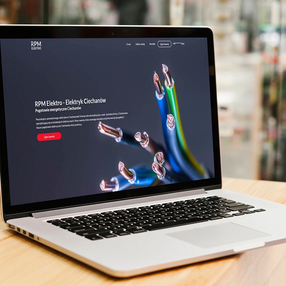 Laptop wyświetla stronę internetową firmy elektrycznej RPM Elektro z Ciechanowa, z grafiką przewodów elektrycznych na ciemnym tle, widoczna klawiatura i część obudowy laptopa na drewnianym biurku.