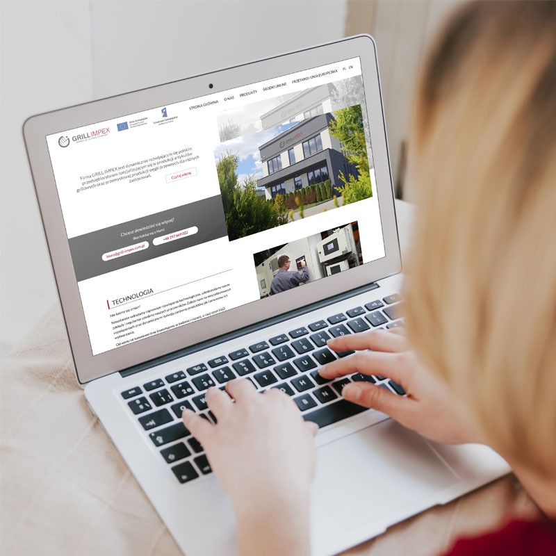 Osoba pisze na laptopie, na ekranie widoczna strona internetowa firmy Grill-Impex z widocznym budynkiem firmy i zakładem produkcyjnym.