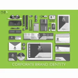 Zestawienie elementów identyfikacji wizualnej firmy: wizytówki, papier firmowy, koperty, długopis, pendrive, notatnik, tablet, smartfon i laptop z logo, ułożone na zielonym tle.