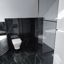 Nowoczesna łazienka z czarnymi płytkami imitującymi marmur, biała wisząca toaleta, kabina prysznicowa z czarnymi ramami i mozaikowa obudowa wanny.