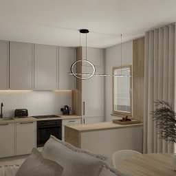 Mudi Agnieszka Kasprzyk - Jasna kuchnia z drewnianymi akcentami, minimalistycznym oświetleniem i rośliną w wazonie na stole. Widok na okno z zasłonami.