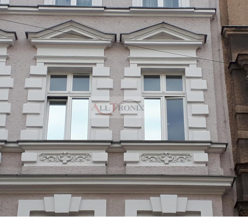 Elewacja budynku w Szczecinie z dwoma oknami, z których jedno ma wyraźnie odbijające światło szkło.