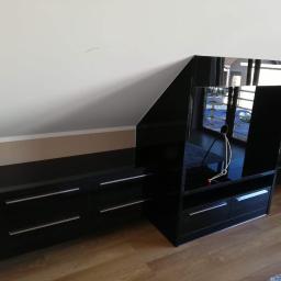 Awan Meble - Czarna, lakierowana zabudowa pod skosem na poddaszu, z szafkami i regałem, widoczne odbicie okna.