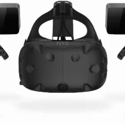 Zestaw do wirtualnej rzeczywistości HTC Vive: gogle VR, dwa kontrolery i dwa sensory bazowe, wszystko w kolorze czarnym, na białym tle.