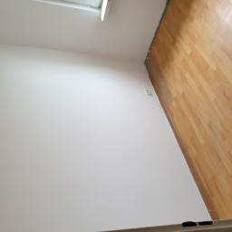 Grzegorz Drz - Pokój po malowaniu ścian na biało i ułożeniu paneli podłogowych z widocznym gniazdkiem elektrycznym na ścianie