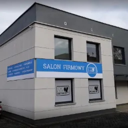 Budynek firmy z szyldem 'Salon Firmowy', oferującej monitoring, kontrolę dostępu, alarmy, oświetlenie LED i systemy parkingowe, z logo 'MW Security' i 'MW Power' w oknach.