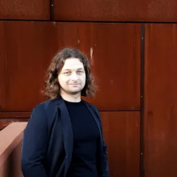 Portret architekta na tle ściany z paneli kortenowskich