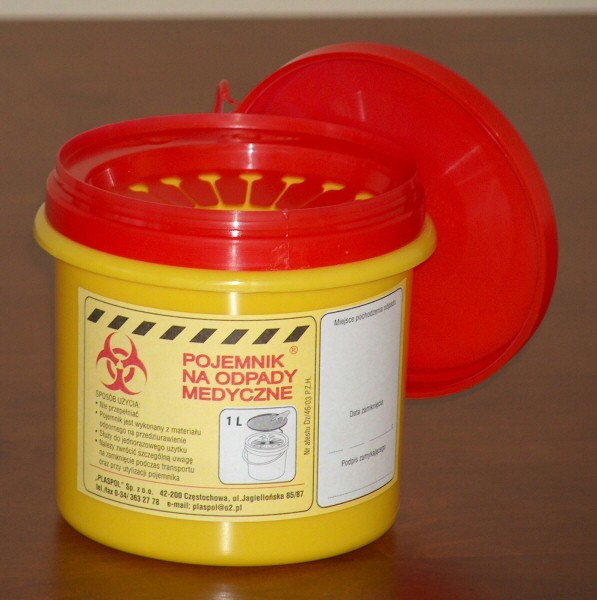 Żółty pojemnik na odpady medyczne z czerwoną pokrywą, otwarty, z widocznymi instrukcjami użytkowania i ostrzeżeniem o zagrożeniu biologicznym.