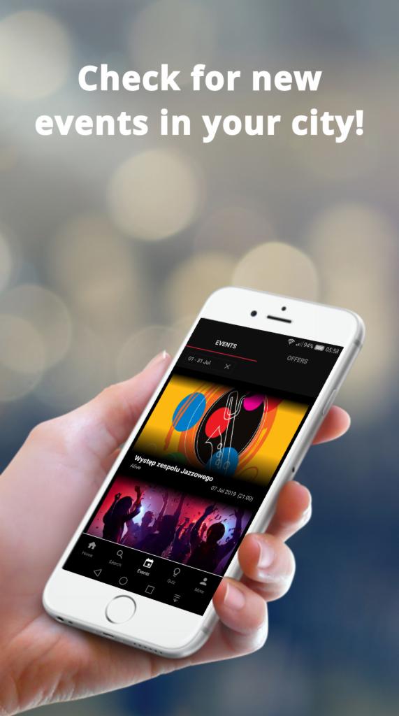 Smartfon w dłoni wyświetlający aplikację z ofertami wydarzeń kulturalnych, w tle rozmyte światła bokeh.