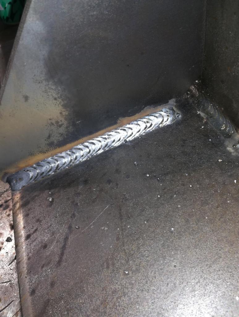 Wewnętrzny narożnik konstrukcji ze stali, z widocznym świeżym spawem o charakterystycznym wzorze jodełki, na powierzchni widoczne ślady po obróbce.