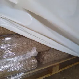 Paleta z workami pelletu zabezpieczona folią stretch i białym workiem ochronnym przed warunkami atmosferycznymi.