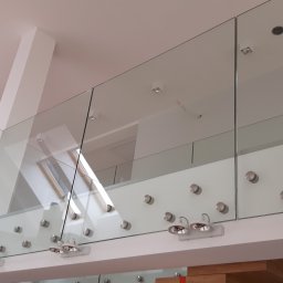 Dariusz Stepa METAL-HOUSE - Szklana balustrada wewnętrzna na antresoli, mocowana punktowo, widok z dołu, oświetlenie halogenowe.