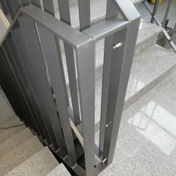 Dariusz Stepa METAL-HOUSE - Szare schody z granitowych płytek z nowoczesną, metalową balustradą o prostych, pionowych szczeblach, mocowaną na śruby.