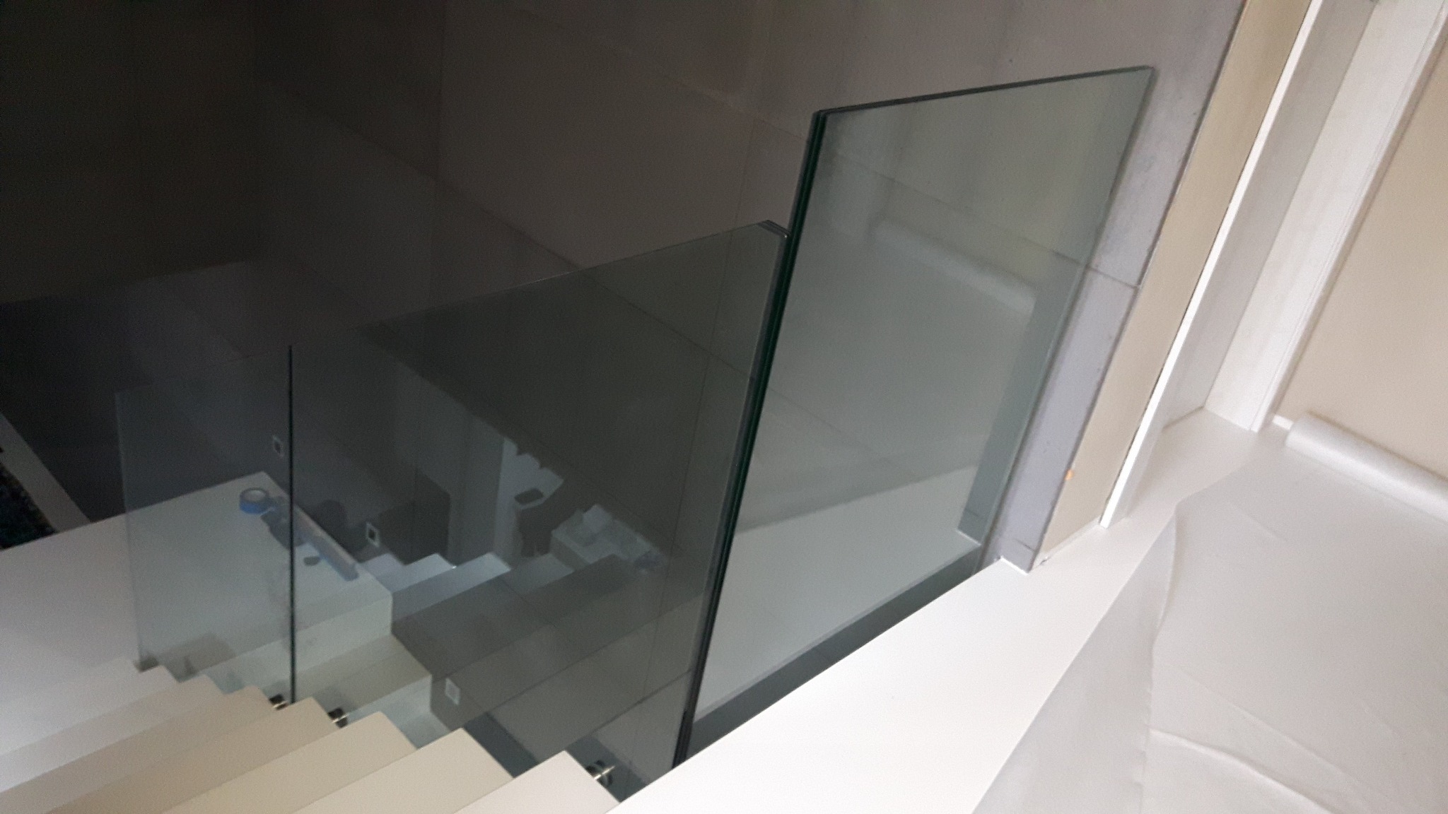 Nowoczesne schody z białymi stopniami i szklaną balustradą, widok z góry z lekkim efektem rozmycia.