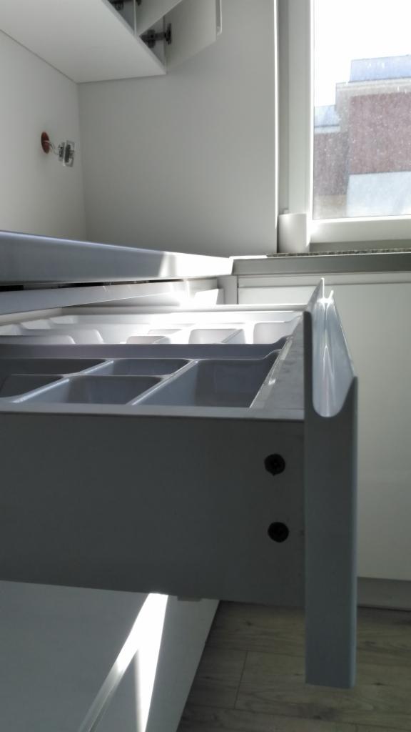 Wysunięta szuflada z przegródkami na sztućce w białej zabudowie kuchennej, widok z boku, realizacja w Suwałkach.