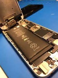 Otwarty smartfon z widoczną baterią Li-ion, podczas wymiany lub serwisu, na niebieskim podłożu.