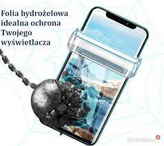 Smartfon zabezpieczony folią hydrożelową, z symulacją kuli uderzającej w ekran, prezentacja odporności na uszkodzenia.