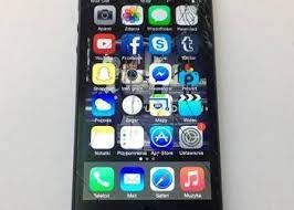 Smartfon z pękniętym ekranem prezentujący ekran główny z ikonami aplikacji. Widoczne uszkodzenia w górnej części obudowy.