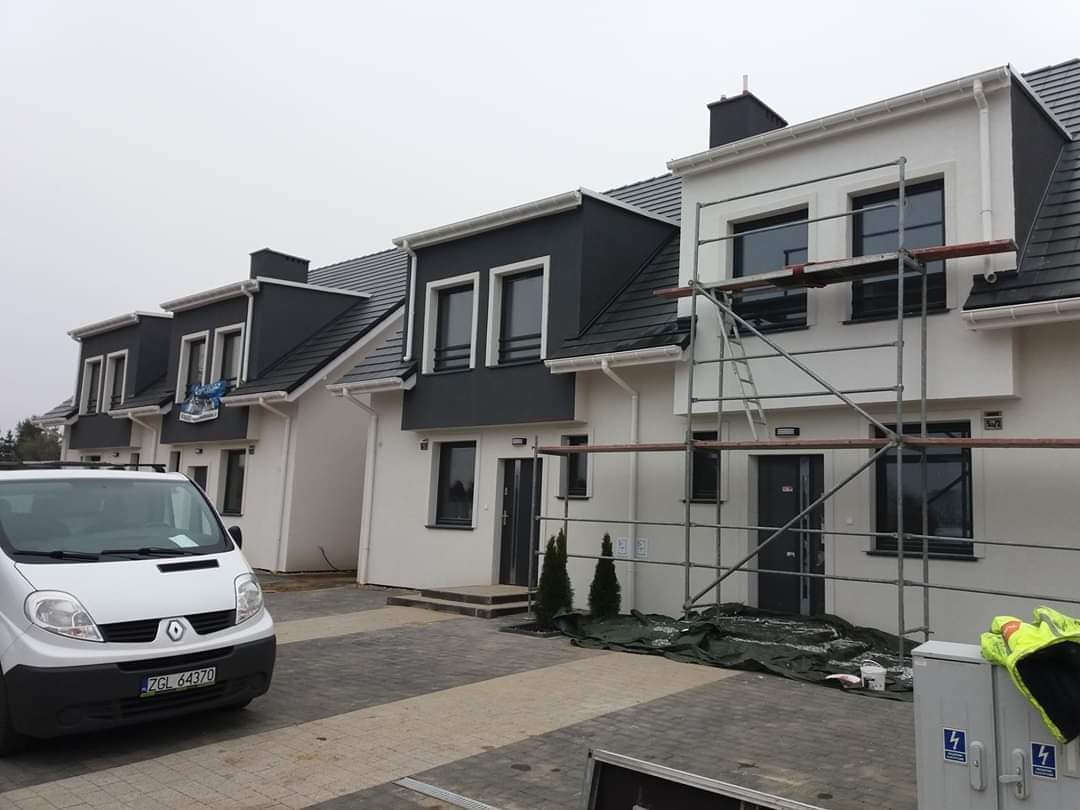 Szeregówka domów jednorodzinnych w trakcie prac elewacyjnych, widoczne rusztowania i samochód dostawczy firmy, Szczecin.