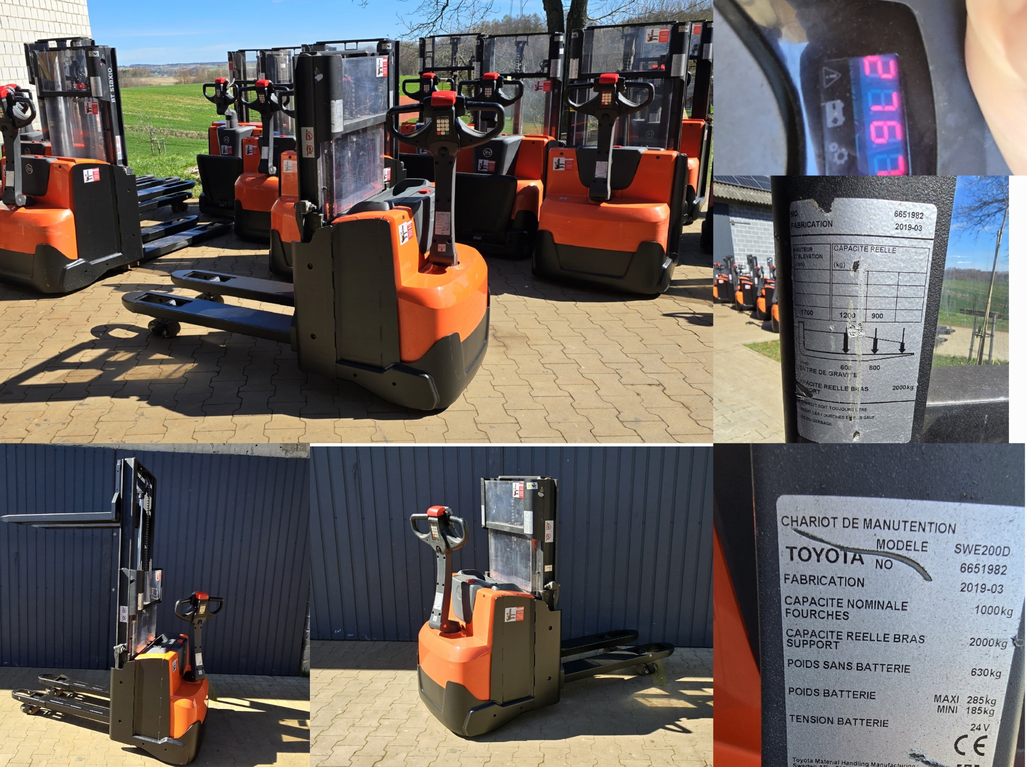 Pomarańczowo-czarne wózki paletowe elektryczne Toyota SWE200D ustawione na zewnątrz na brukowanym placu, widoczne detale tabliczki znamionowej z datą produkcji 2019-03 oraz wskazania wyświetlacza.
