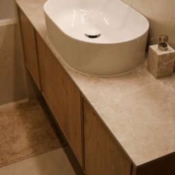 Mebel-Ol - Nowoczesna łazienka: owalna umywalka nablatowa na drewnianej szafce z marmurowym blatem, obok dozownik mydła z tego samego marmuru. Ujęcie z bliska.