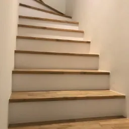 Betonowe schody zabiegowe w okładzinie z Dębu Avangard, z podstopnicami z białej płyty meblowej.