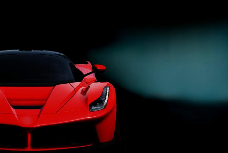Częściowy widok czerwonego, sportowego samochodu na ciemnym tle, z wyraźnie widocznym przednim reflektorem LED.