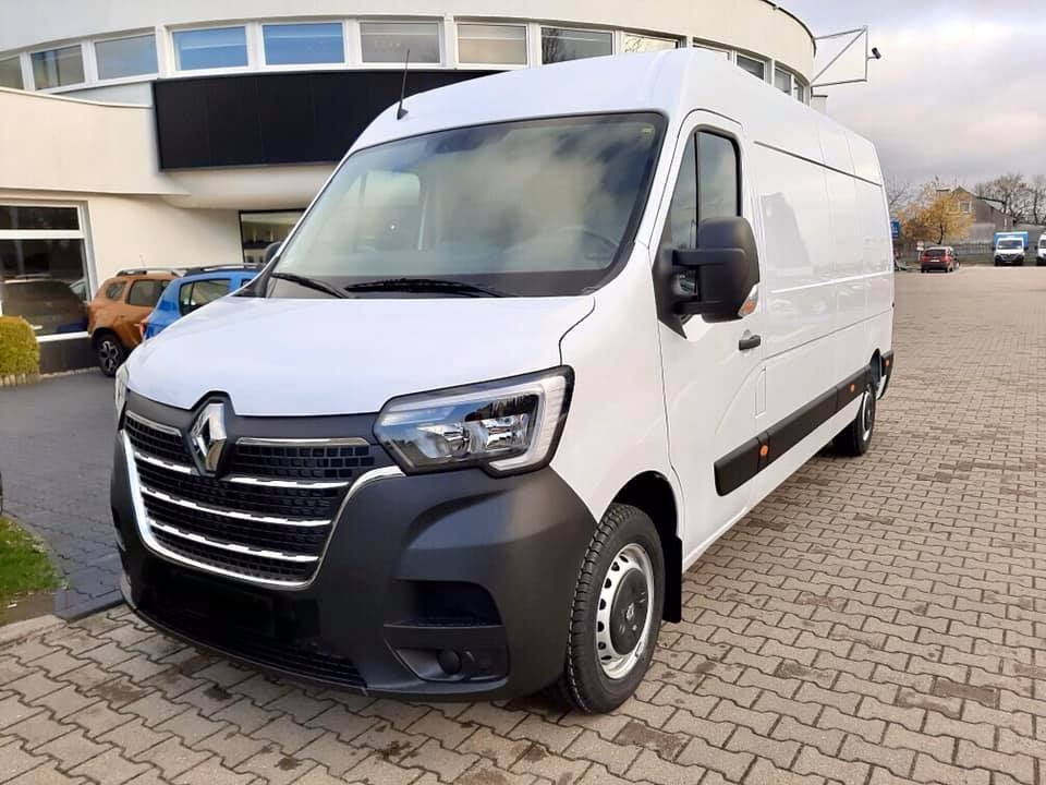 Biały samochód dostawczy Renault Master na parkingu z kostki brukowej, widok z przodu i boku, z budynkiem w tle.