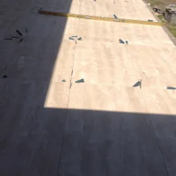 Układanie jasnych, beżowych płyt tarasowych z użyciem poziomicy i klinów dystansowych na przygotowanym podłożu w ogrodzie.