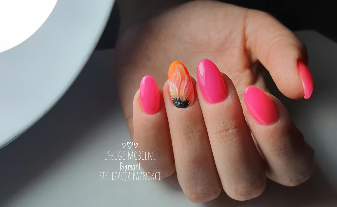 Dłoń z neonowo różowymi paznokciami w kształcie migdała, jeden paznokieć ozdobiony motywem kwiatowym w odcieniach pomarańczy i bieli z czarnym środkiem, widoczne logo firmy 'Usługi mobilne Diamant...