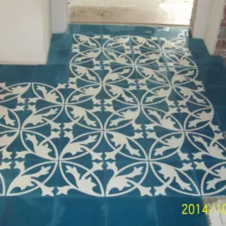 Niebieskie płytki podłogowe z kremowobiałym, roślinnym wzorem, ułożone w przejściu między pomieszczeniami; widoczne surowe ściany i data wykonania zdjęcia.