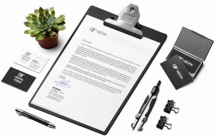 Biurko z czarnym klipsem trzymającym list firmowy 'GF GRUPA', wizytówki, pióro, cyrkiel, spinacze i sukulent w doniczce, prezentacja identyfikacji wizualnej firmy.